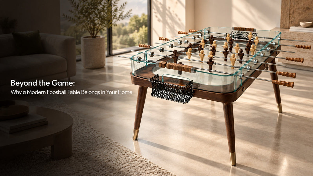 ARGMAC modern foosball table with glass sides, walnut frame and brass-tipped legs, wooden foosball characters in dark and natural finish, in a sunlit luxury living room.