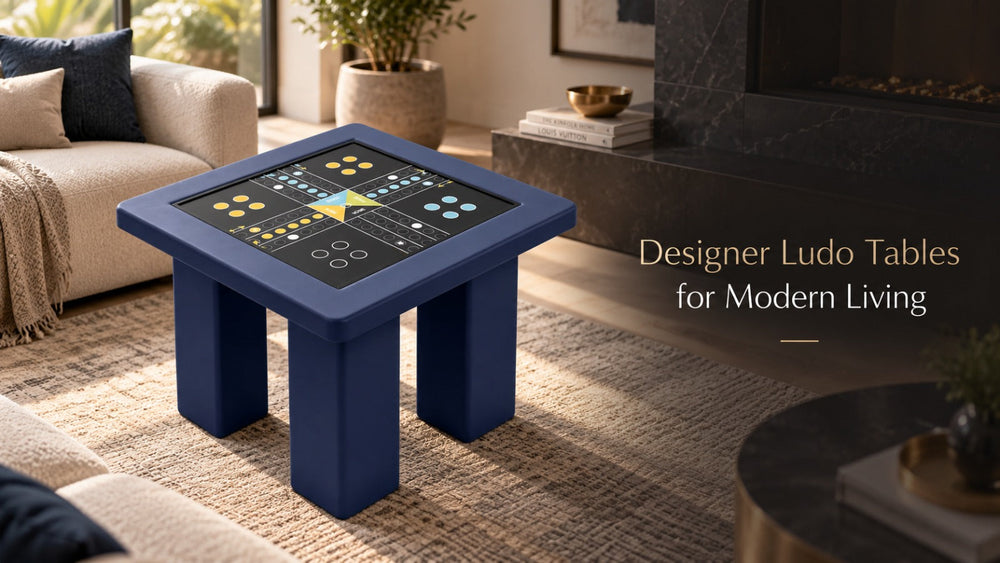 ARGMAC navy blue square designer table on a woven rug in a modern living room, its black ludo table top showing a printed board with yellow, blue and white ludo pieces in each home.