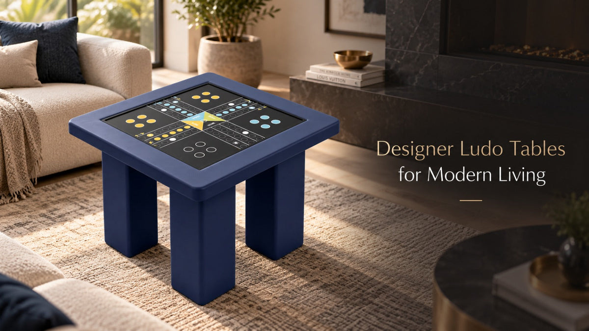 ARGMAC navy blue square designer table on a woven rug in a modern living room, its black ludo table top showing a printed board with yellow, blue and white ludo pieces in each home.